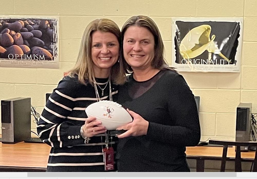 Two women holding football with eagle on it