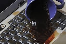 Computer keyboard with a spilled mug of coffee on it.