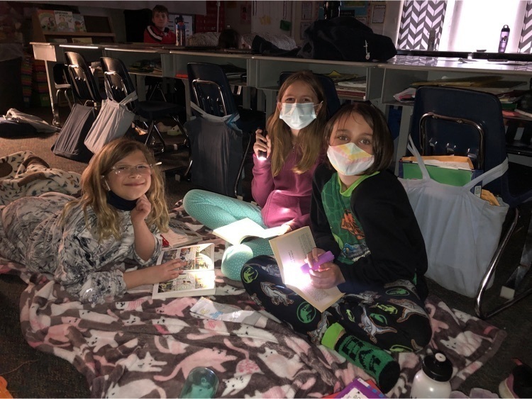 Three students reading books by flashlight in a darkroom