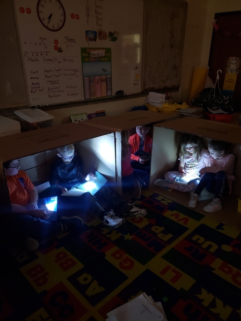 Students reading books with flashlights in a dark room