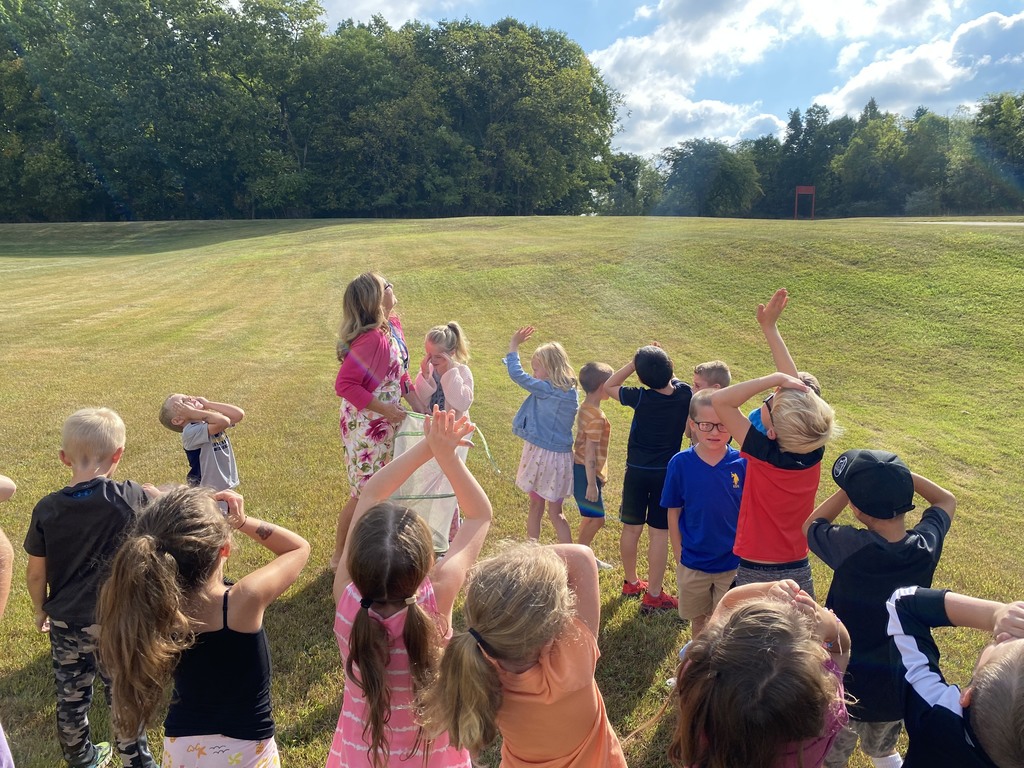 Children watching a recently hatched butterfly fly away.