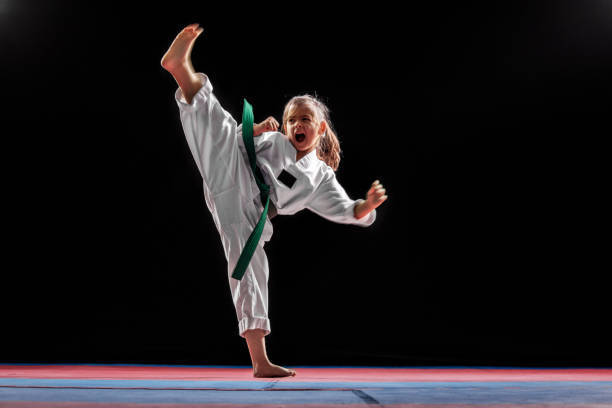Girl in a white Karate uniform performing a Karate kick