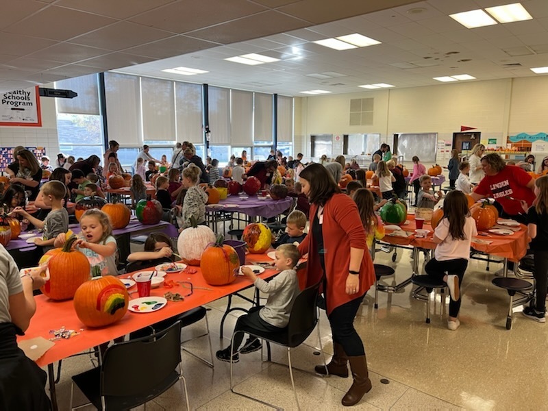 Parent volunteers and children decorating pumpkins.