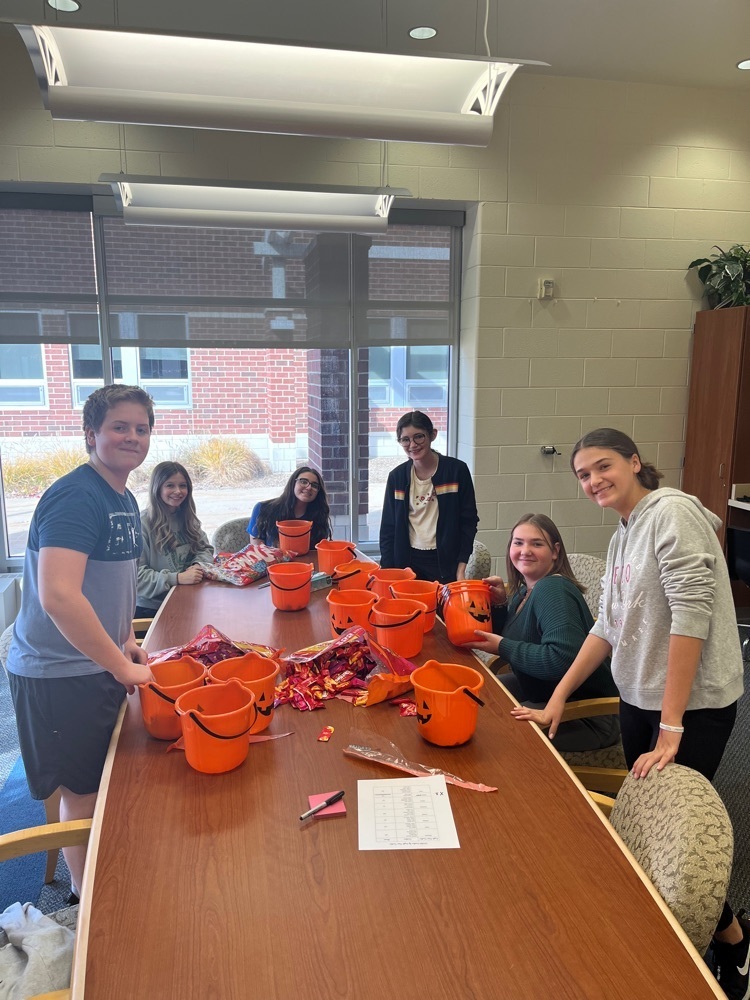 Students around a table with pumpkin buckets and candy￼