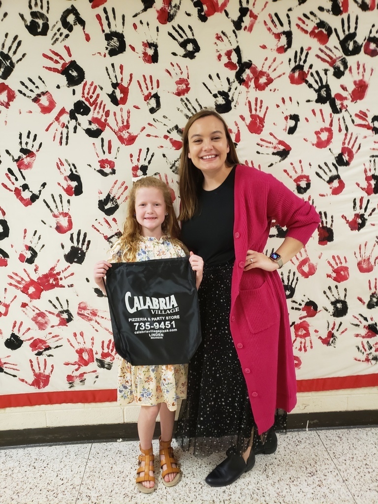 Student and teacher standing infront of a banner with black and red handprints