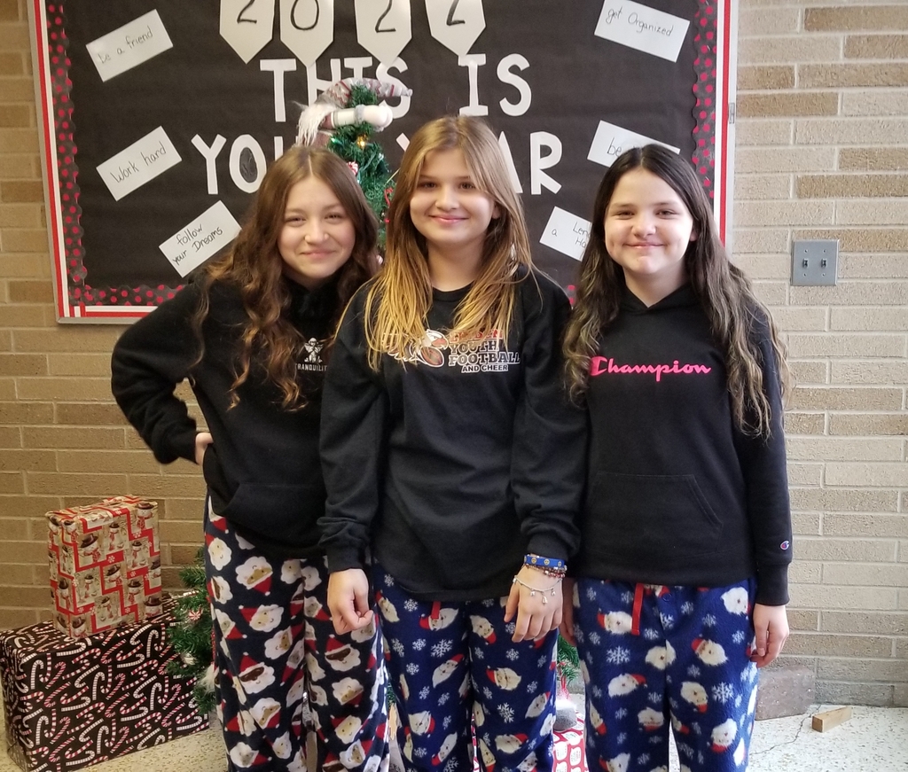three girls each wearing blue pants with Santa faces printed on them and a black long sleeve shirt.
