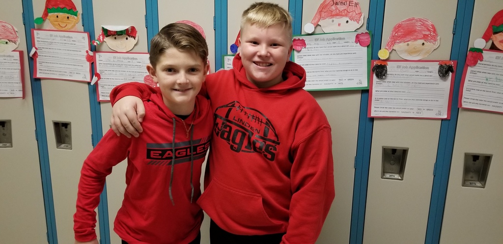 2 boys standing with an arm over each other's shoulder, wearing red Eagle's hoodies and black pants.