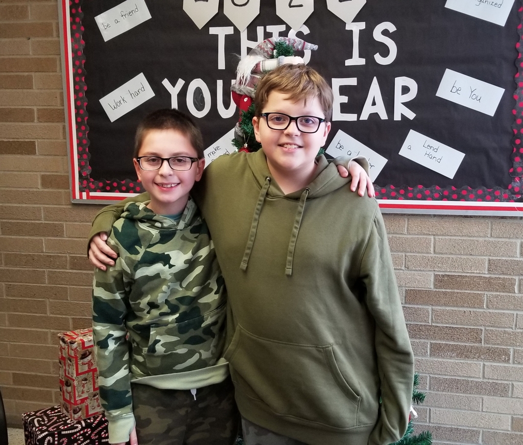 2 boys standing next to each other wearing green hoodies.