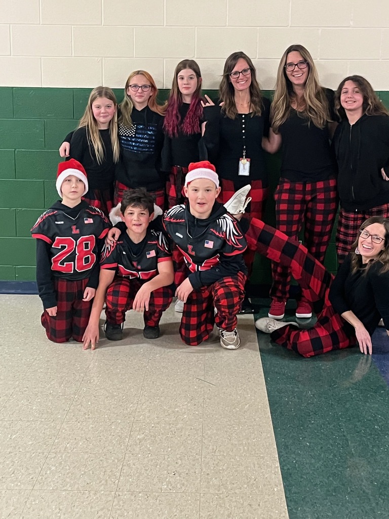 A group of adults and students wearing black shirts and red and black checkered pants.