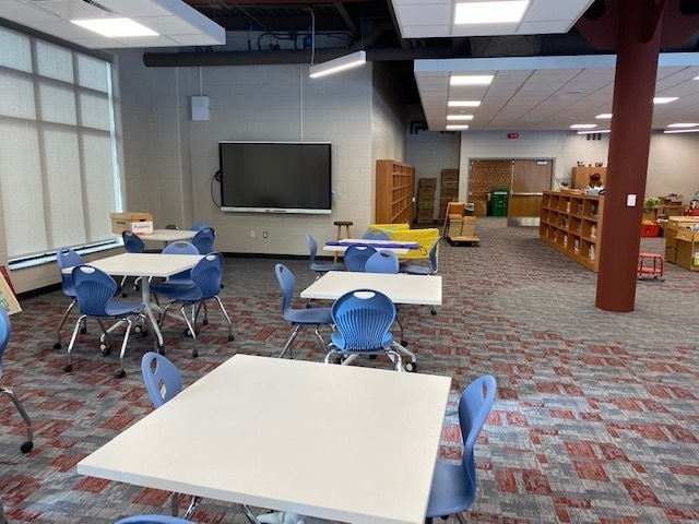 collaboration zone with student tables and chairs with instructional monitor hanging on wall in media center at Linden Elementary