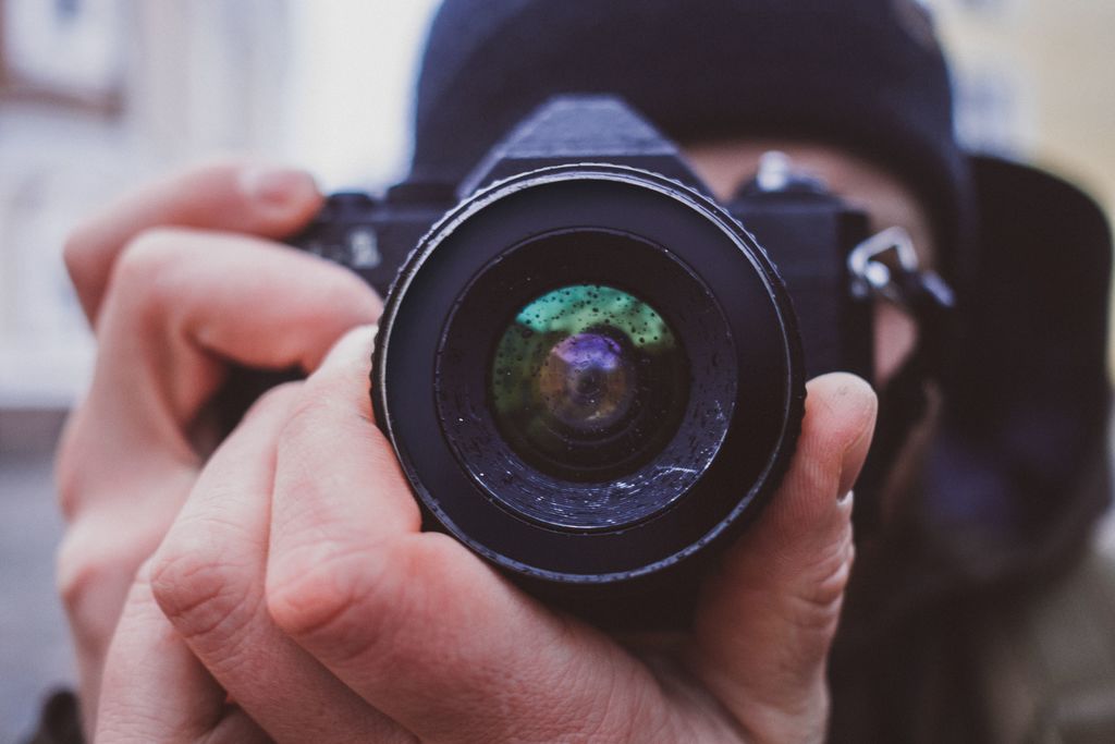 Hands holding a black camera preparing to take a picture