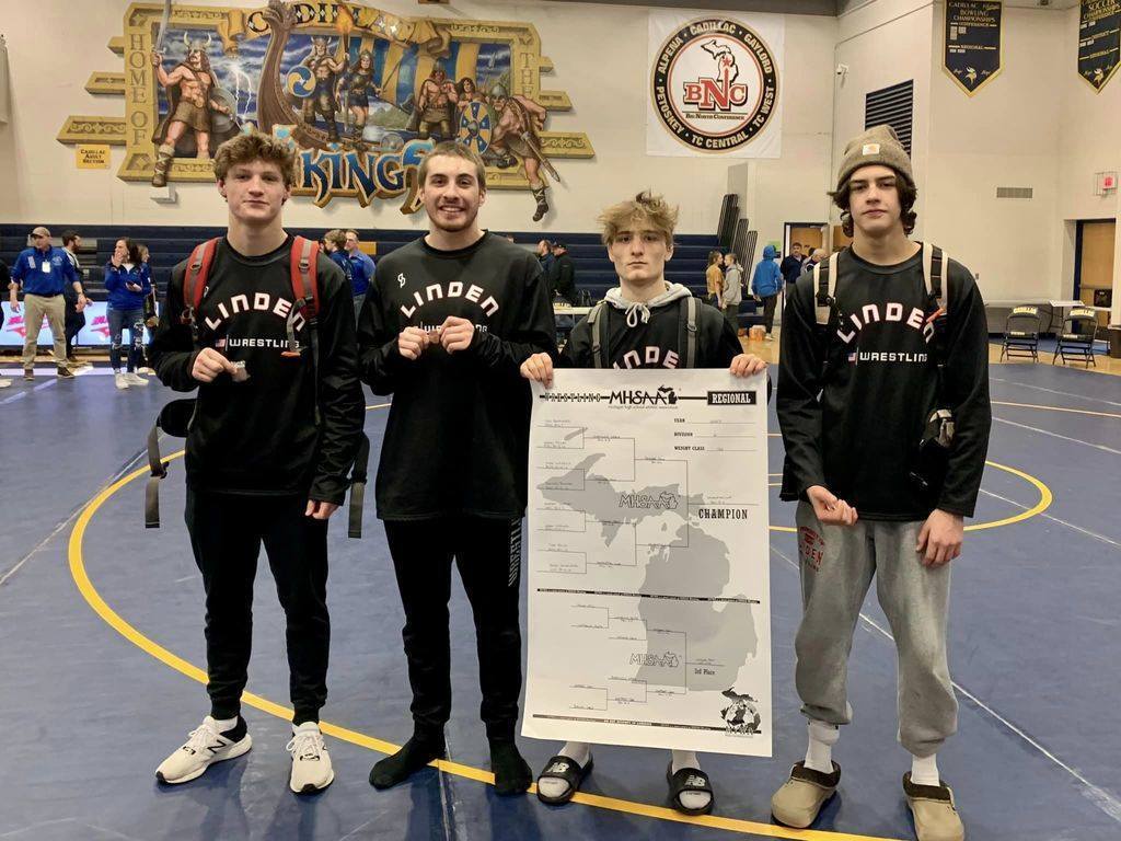 Four wrestlers holding a bracket poster