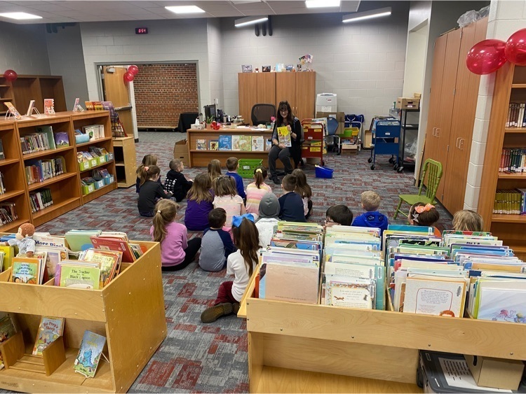 A librarian reading a story to a group of students in a library.
